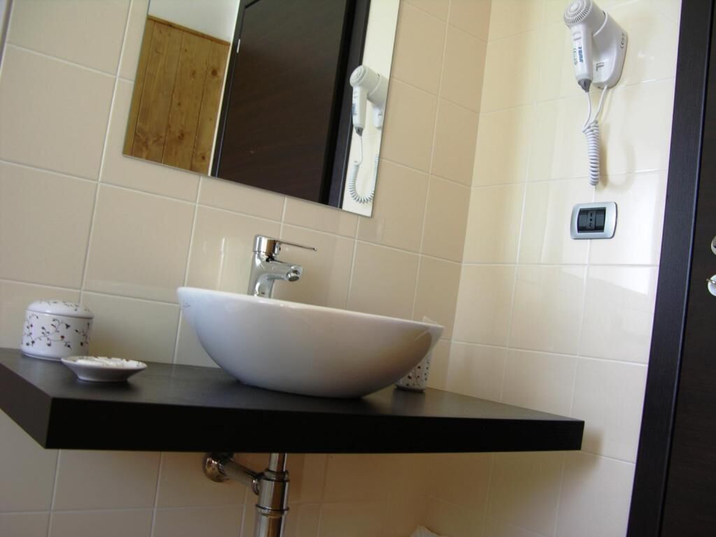 A bathroom with a white sink, a mirror, a hairdryer, and a digital scale on the wall.