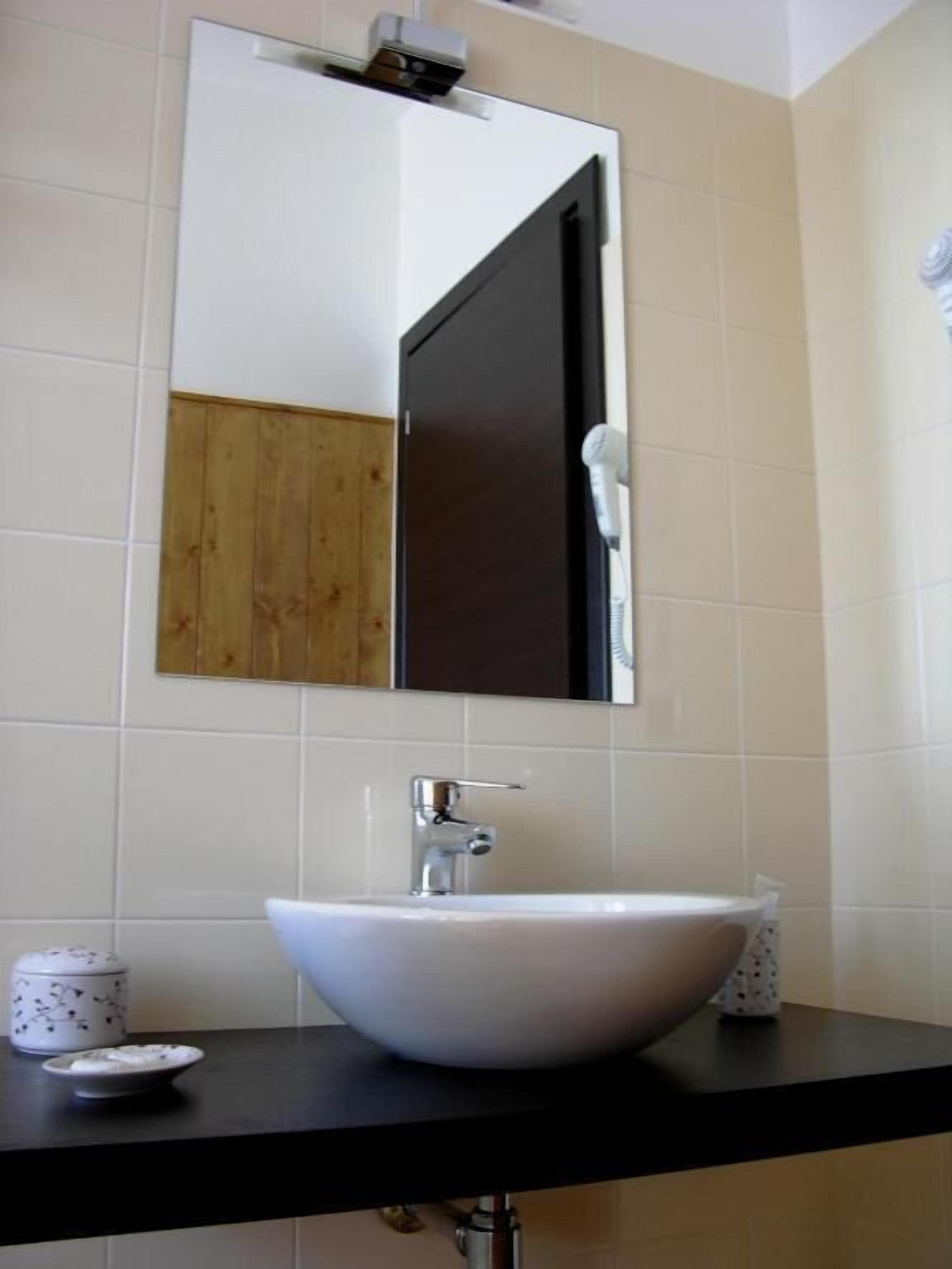 A bathroom with a white sink, a mirror, and a hairdryer.