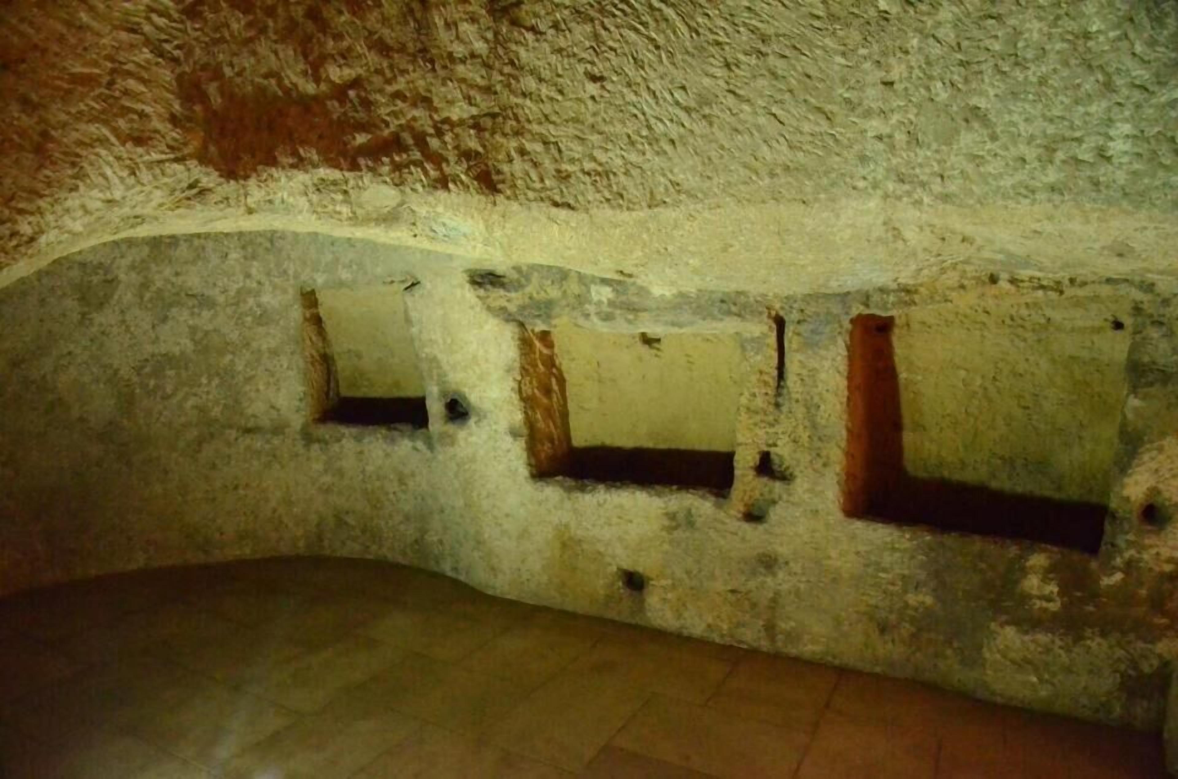 A room with a textured, cave-like ceiling and walls, featuring three small, rectangular windows.
