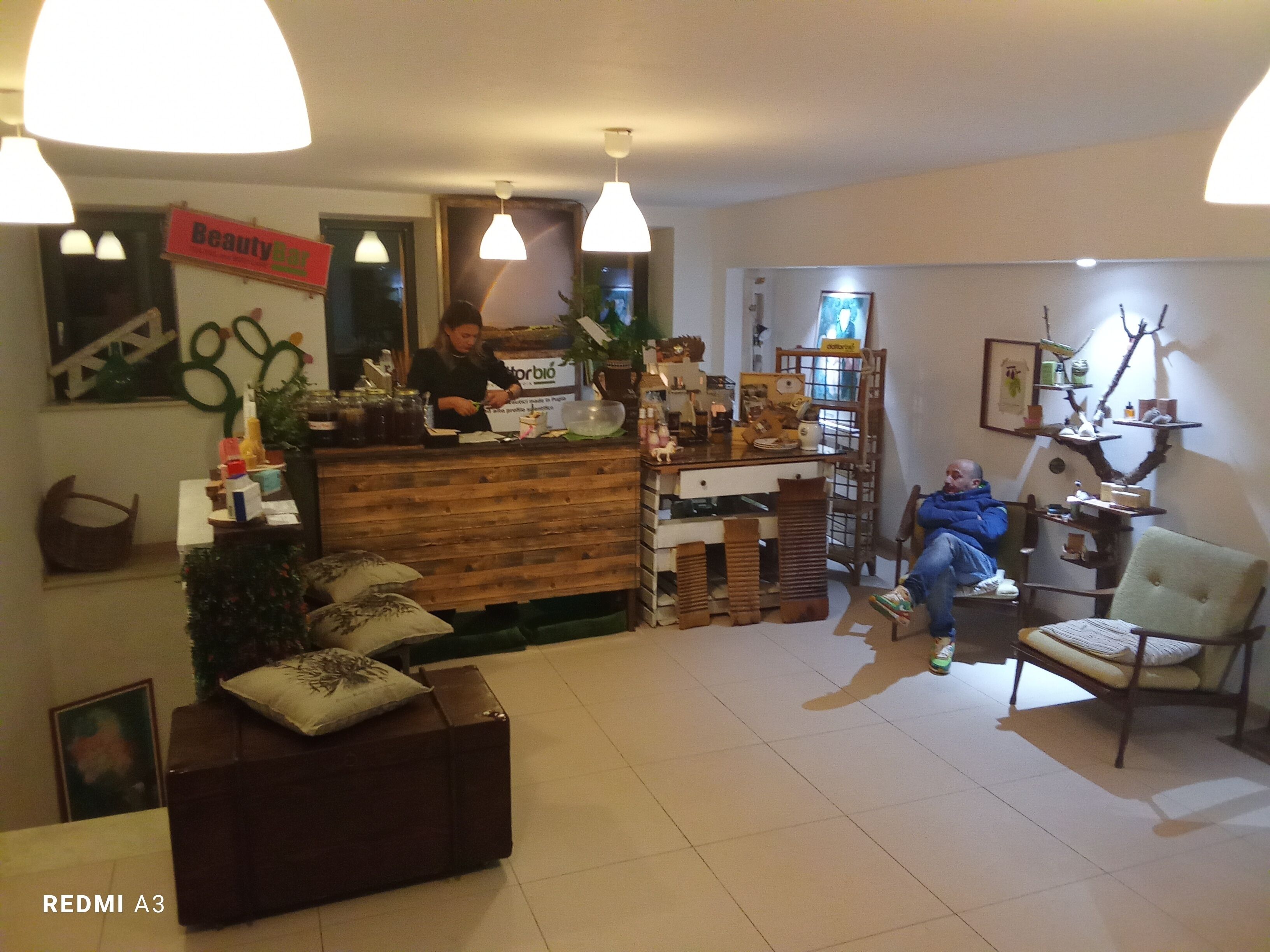 A reception area with a wooden counter, a seated receptionist, and a customer seated on a couch.