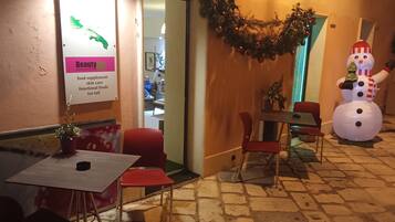 An outdoor seating area with red chairs and a table, a sign for 'Beauty & Health' offering food supplements and skincare, and a snowman decoration.
