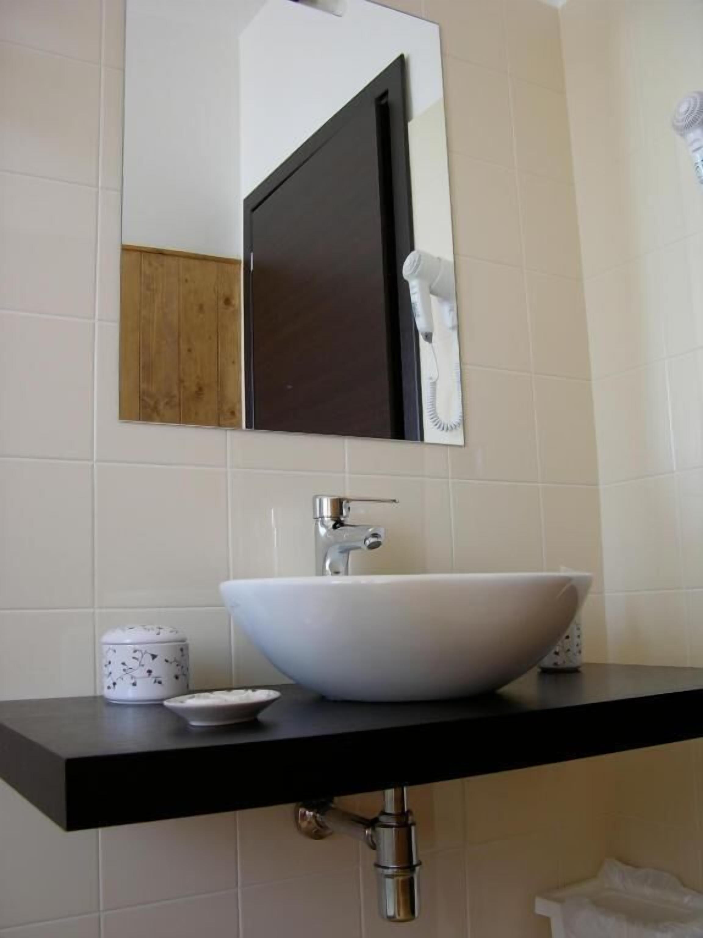 A bathroom with a white sink, a mirror, and a towel hanging on the wall.