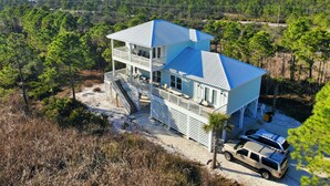Una casa a due piani con tetto blu, un balcone e un'auto parcheggiata davanti.