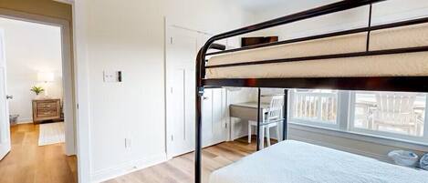 Habitación con literas, un escritorio, una silla, un armario pequeño y una ventana con vistas.
