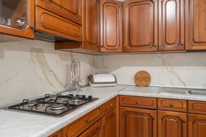 Eine Küche mit Holzausstattung, einem Gasherd, einem Toaster und einer Marmorarbeitsplatte.
