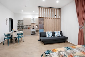 A compact living space with a kitchenette, a dining area, and a sofa.