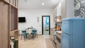 Una cocina moderna con un refrigerador azul, armarios de madera y un comedor con sillas y una mesa.