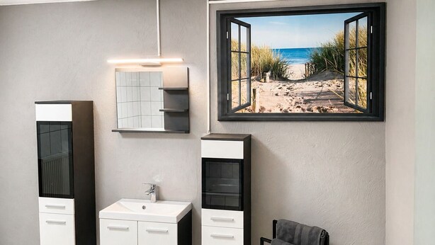 Une salle de bain avec une grande fenêtre, un lavabo, un miroir et un porte-serviettes.