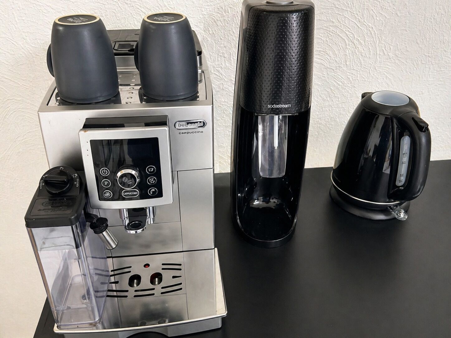 De’Longhi-merkkinen espressokone, jossa on digitaalinen näyttö, sekä suodatinkahvinkeitin ja kahvipannu.