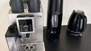 De’Longhi-merkkinen espressokone, jossa on digitaalinen näyttö, sekä suodatinkahvinkeitin ja kahvipannu.