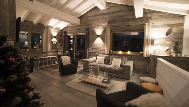 A modern living room with a wooden ceiling, a glass coffee table, and a Christmas tree.
