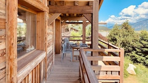 A wooden cabin with a balcony overlooking a mountainous landscape.