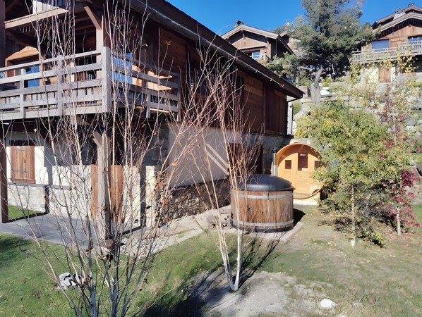 A wooden building with a balcony, a stone wall, and a wooden barrel.