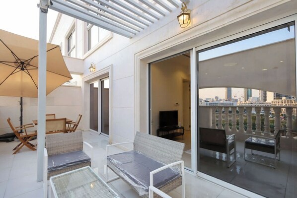 A balcony with a table, chairs, a sofa, and a TV.