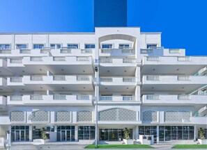 A multi-story hotel with balconies, a central entrance, and decorative lattice work.