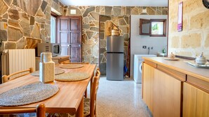 Eine Küche mit Steinwänden, Holzmöbeln, einem Kühlschrank und einem Fenster.