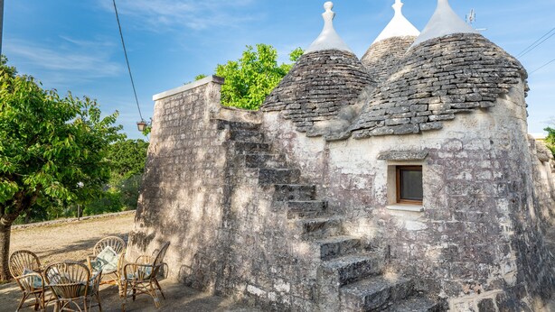 Ein rustikales Steinhaus mit einer Treppe, die zu einem kleinen Fenster führt.