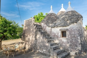 A rustic stone building with a staircase leading to a small window.