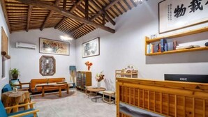 Una habitación con techo de madera, televisor, estantería, sofá, mesa y sillón.