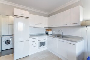 A modern kitchen with white cabinetry, a built-in washing machine, and a microwave.