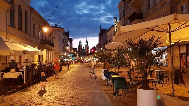 A cobblestone street lined with outdoor seating and a hotel sign.