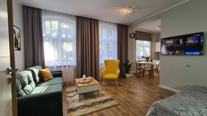 A modern living room with a sofa, a yellow armchair, a coffee table, and a TV mounted on the wall.