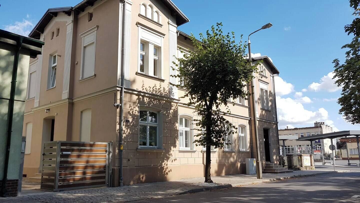 Um edifício de vários andares com fachada bege, janelas amplas e um portão de metal.