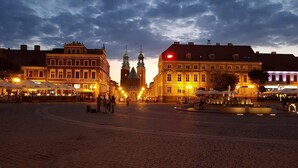 Una plaza histórica con pavimento de adoquines, arquitectura europea tradicional y zonas de estar al aire libre.