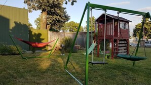 Un parque infantil con columpios y una casita roja.