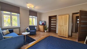 Una sala de estar moderna con un sofá, un televisor, un armario de madera y un ventanal grande.