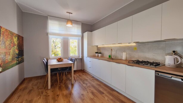 Una cocina moderna con armarios blancos, encimera de madera y estufa a gas.
