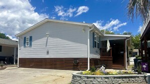 A single-story house with a garage, a covered porch, and a stone flower bed. - 1560 Mason Circle located in The Keys (Surfside Beach)