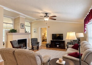 A living room with a fireplace, a ceiling fan, a television, and a sofa. - 1560 Mason Circle located in The Keys (Surfside Beach)