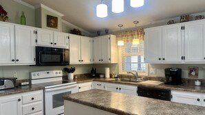 A kitchen with white cabinets, a microwave, stove, and a coffee maker. - 1560 Mason Circle located in The Keys (Surfside Beach)