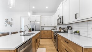 A modern kitchen with white cabinetry, stainless steel appliances, and a wooden floor. - Villa #18 Bloomington Country Club: Pool, Golf, Restaurant (St. George)