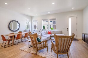 A modern living room with a dining area, a sofa, and a large mirror.