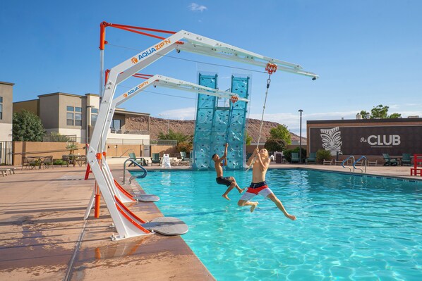 A swimming pool with a slide and climbing wall, surrounded by lounge chairs and a building labeled 'the CLUB'. - Villa #08 at Bloomington Country Club: Pool, Golf, Restaurant (St. George)