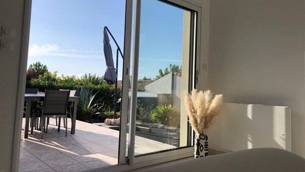 Et værelse med en stor skydedør, der fører ud til en udendørs terrasse.
