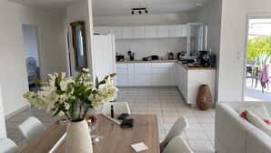 Et moderne køkken med hvide skabe, et spiseområde med et træbord og en hvid sofa.