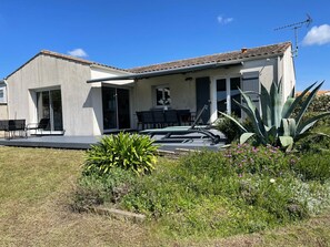 A modern house with a patio, sliding glass doors, and a garden with plants and flowers. - Detached house 1.2 km from the beach (Meschers-sur-Gironde)