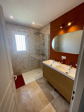 A bathroom with a shower, a sink, a mirror, and a window. - Detached house 1.2 km from the beach (Meschers-sur-Gironde)