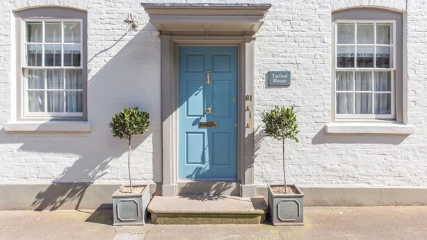 Een wit gebouw met een blauwe deur, twee potplanten en een bordje met de tekst 'Turford House'.