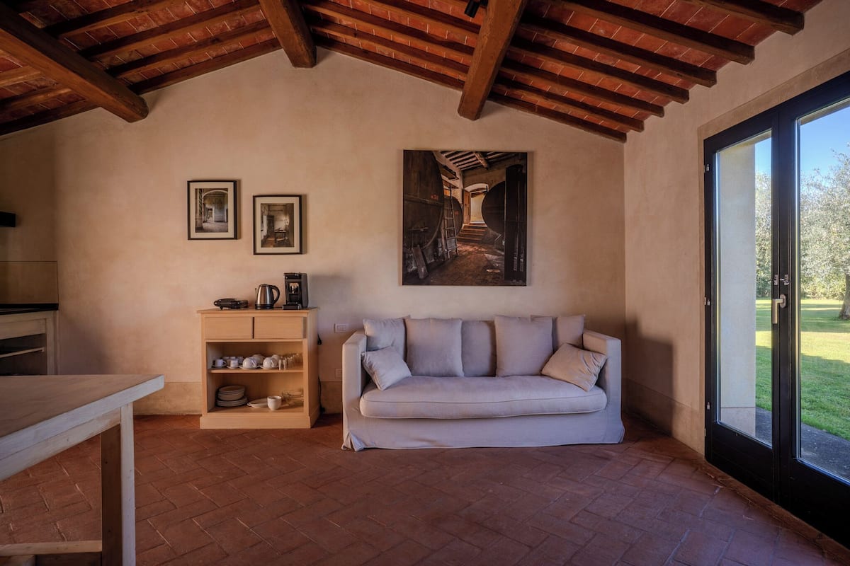 A cozy room with a wooden ceiling, a sofa, a coffee table, and a cabinet with dishes.