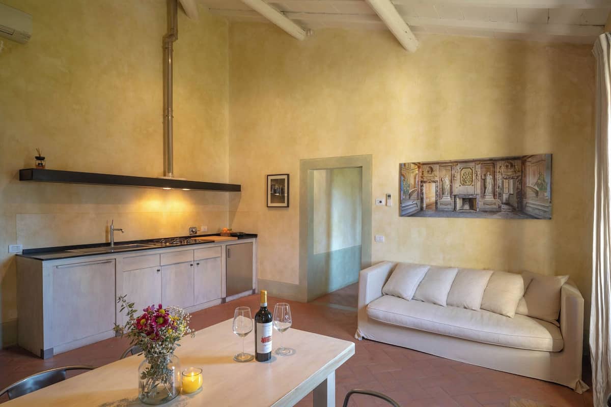 A compact living space with a kitchenette, a dining area with a table and chairs, and a sofa.