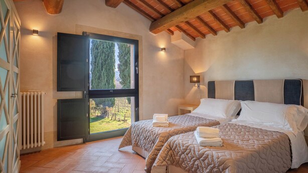 Un dormitorio con dos camas, un ventanal con vistas, un radiador y un techo de madera.
