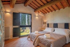 Un dormitorio con dos camas, un ventanal con vistas, un radiador y un techo de madera.