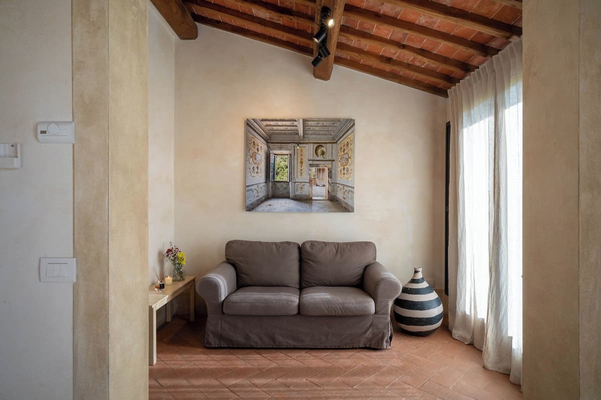 A living room with a brown sofa, a decorative vase, and a wall-mounted painting.