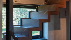 Una escalera moderna de diseño minimalista integrada en una pared de hormigón con un pequeño ventanal.