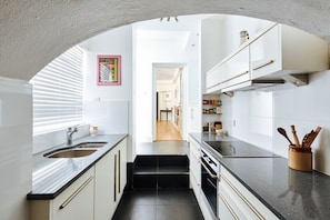 A modern kitchen with white cabinetry, black countertops, and a central island. - Elegant Flat - Notting Hill. Minutes from Hyde Park. (London)
