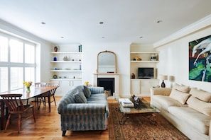 A living room with a sofa, a coffee table, a TV, and a fireplace. - Elegant Flat - Notting Hill. Minutes from Hyde Park. (London)